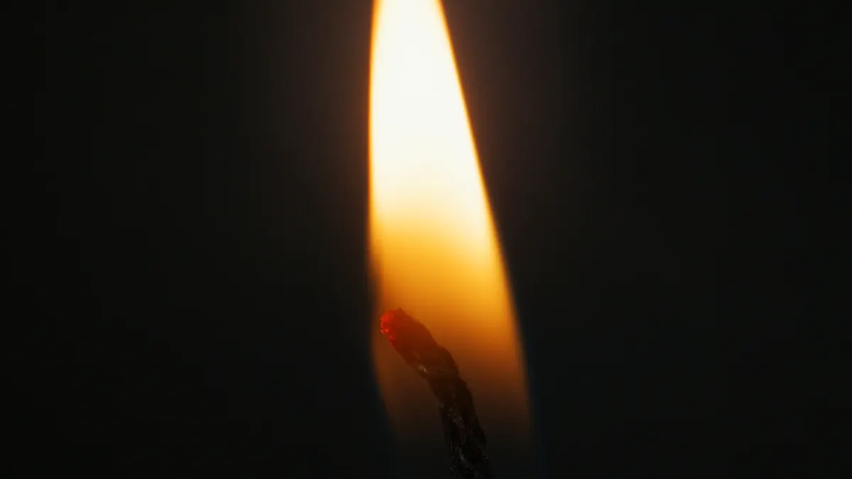 Close-up of a lit candle flame and wick