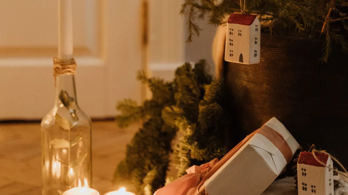 Wrapped gifts and lit candles arranged near a Christmas tree