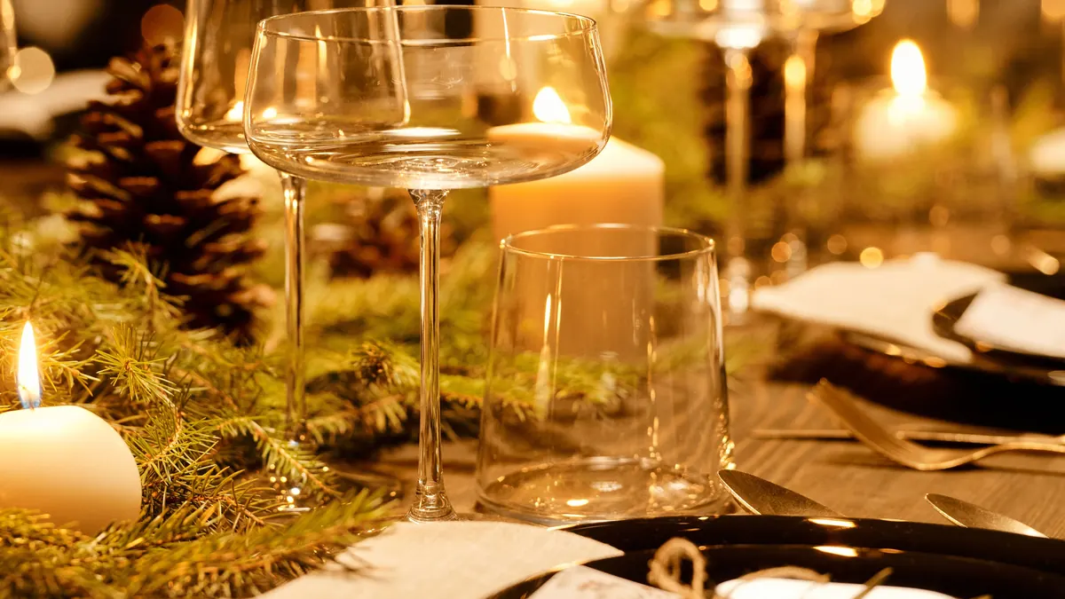 Elegant Christmas dinner table with candles, pine and glassware