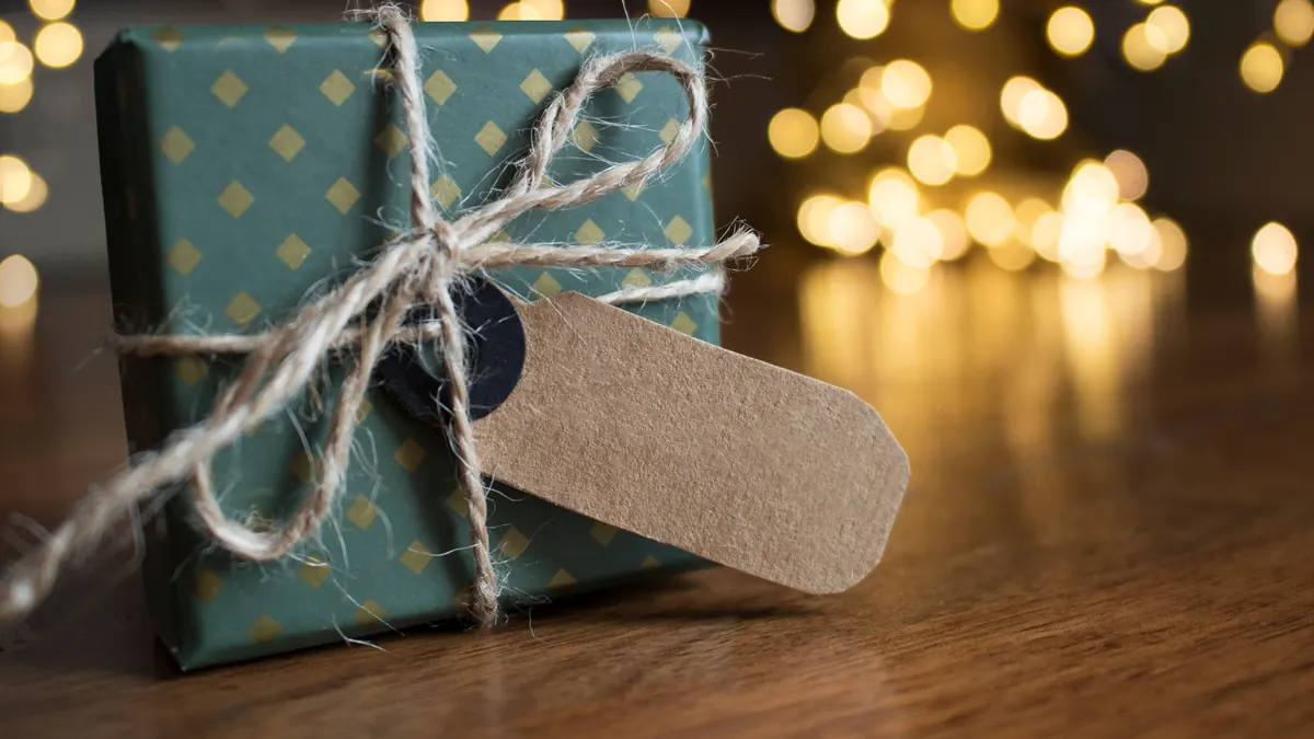 Small wrapped gift with a gift tag and string lights in the background