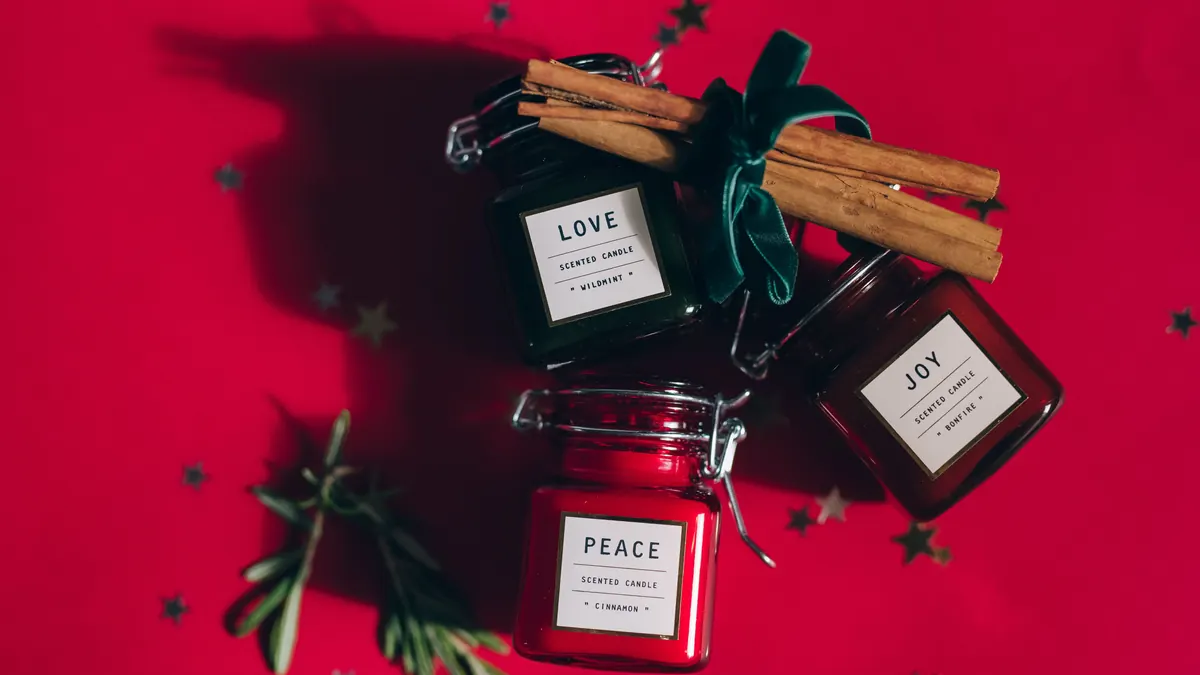 Three small candles labeled with scent names, tied with cinnamon sticks and rosemary